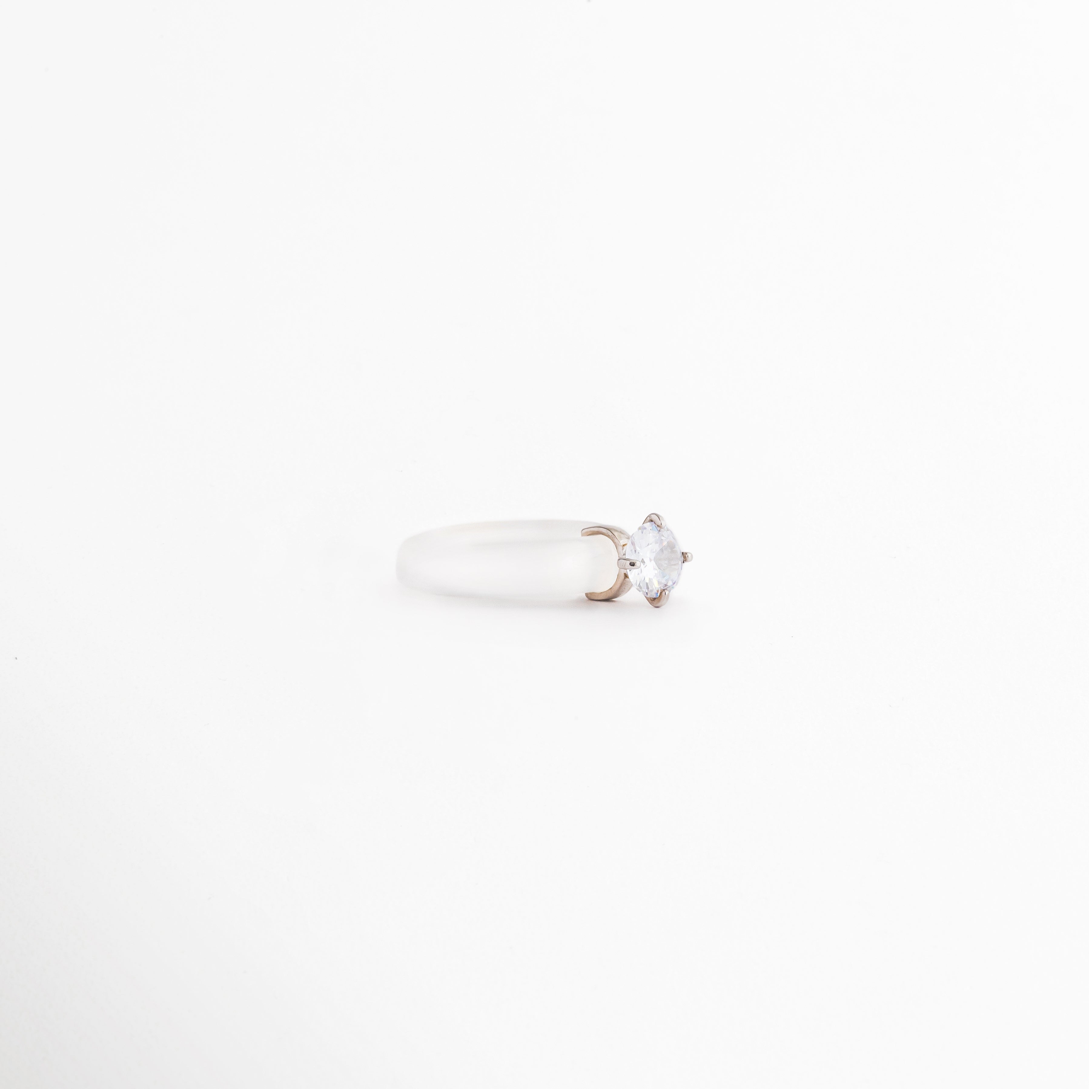 Perfil del Anillo Aeli en plata ley 925 con ágata blanca y zirconia, Vista lateral de anillo minimalista con acabado pulido brillante, Detalle de la montura del Anillo Aeli con piedra central blanca, Anillo de plata con diseño delicado visto de perfil, Vista lateral de anillo elegante con ágata blanca y zirconia.