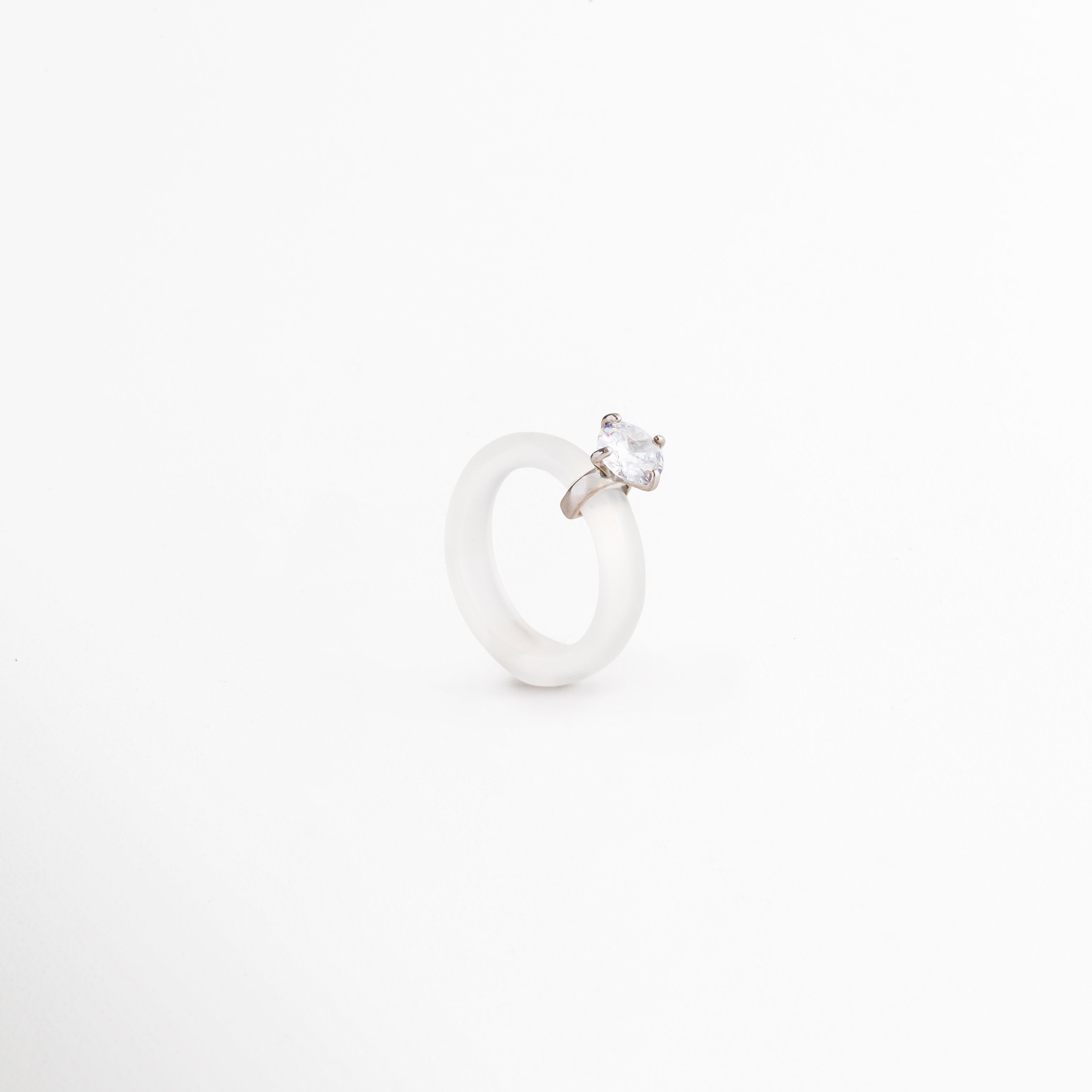 Anillo Aeli desde ángulo lateral mostrando su diseño minimalista, Detalle del anillo de plata 925 con ágata blanca y zirconia brillante, Vista angular de anillo femenino elegante y sofisticado, Anillo refinado con piedra blanca y acabado pulido de alta calidad, Diseño contemporáneo del Anillo Aeli en plata ley 925.