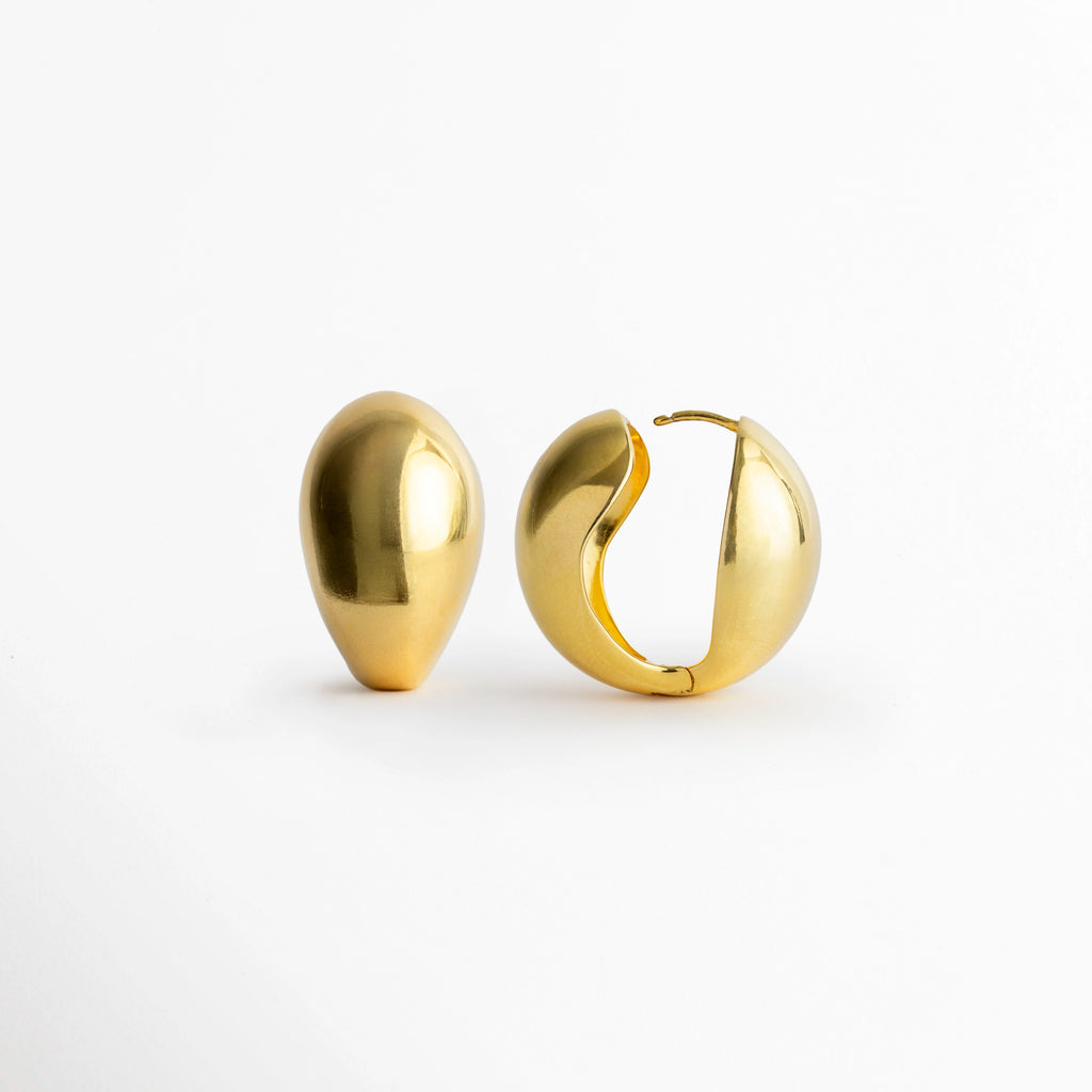 Vista lateral de los Aretes Golden Nevara mostrando la articulación del aro totalmente abierta para colocación, Detalle del broche de encaje oculto y la estructura interna liviana del arete en forma de gota, Muestra del mecanismo de fácil uso y ajuste seguro en el arete abombado enchapado en oro, Vista de cerca de la bisagra articulada de los aretes de volumen fluido sobre fondo claro.