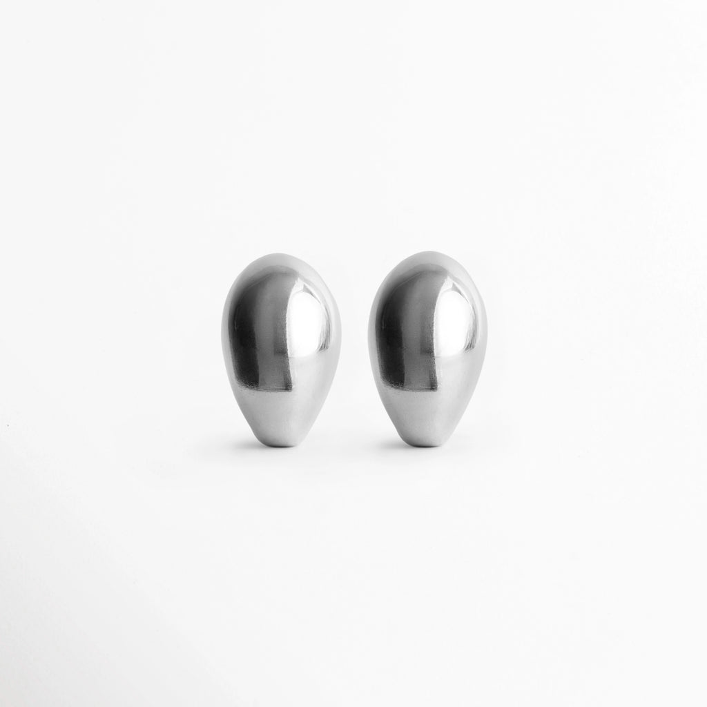 Aretes Silver Nevara abombados en forma de gota esculpida con baño plateado brillante, vista frontal de par sobre fondo blanco, Vista de frente de aretes plateados de volumen redondeado tipo lágrima de 2.7 x 1.8 cm, Par de aretes chunky plateados con silueta orgánica y superficie pulida de alto brillo, Aretes plateados en forma de gota de lluvia estilo gota botánica de inspiración chic francesa.