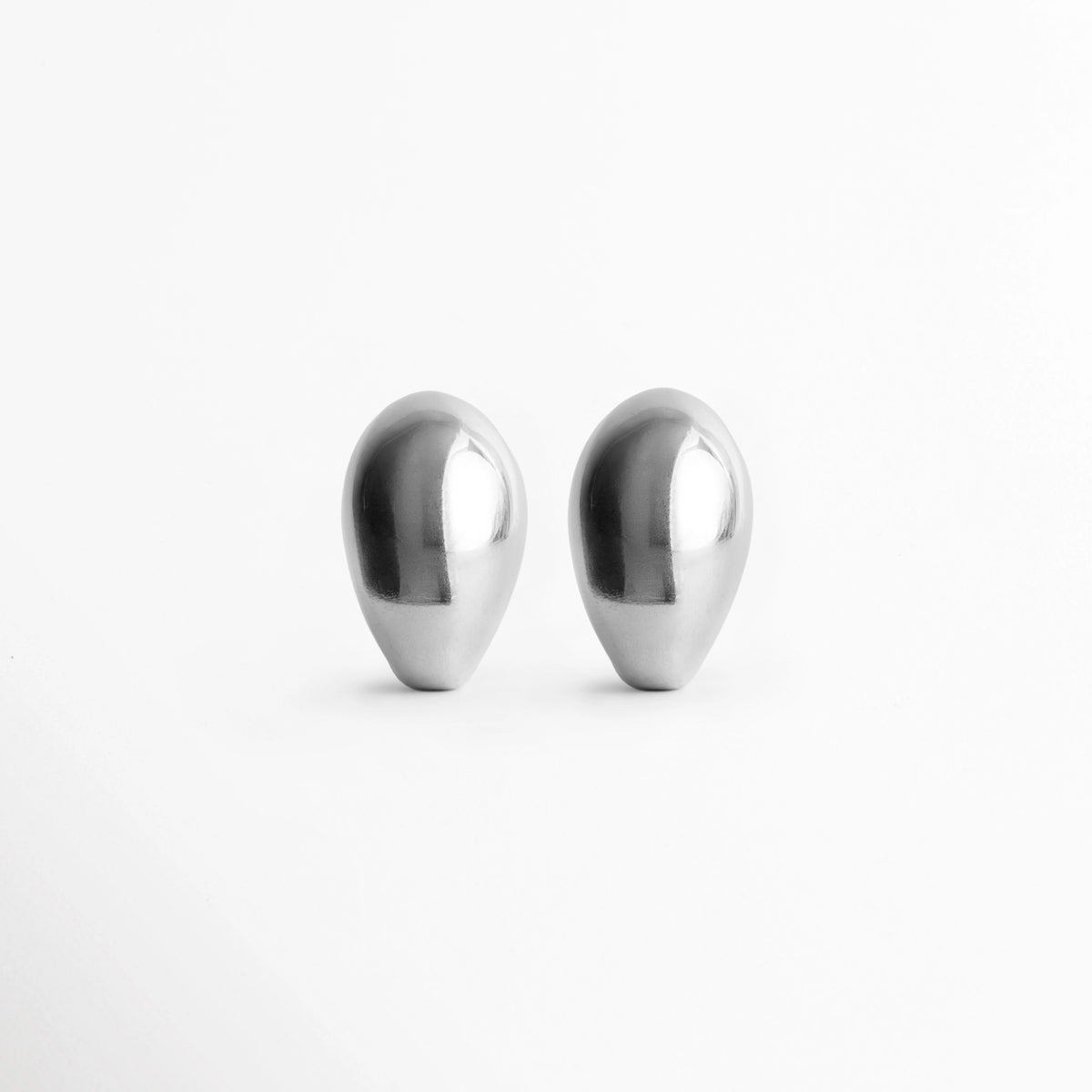 Aretes Silver Nevara abombados en forma de gota esculpida con baño plateado brillante, vista frontal de par sobre fondo blanco, Vista de frente de aretes plateados de volumen redondeado tipo lágrima de 2.7 x 1.8 cm, Par de aretes chunky plateados con silueta orgánica y superficie pulida de alto brillo, Aretes plateados en forma de gota de lluvia estilo gota botánica de inspiración chic francesa.
