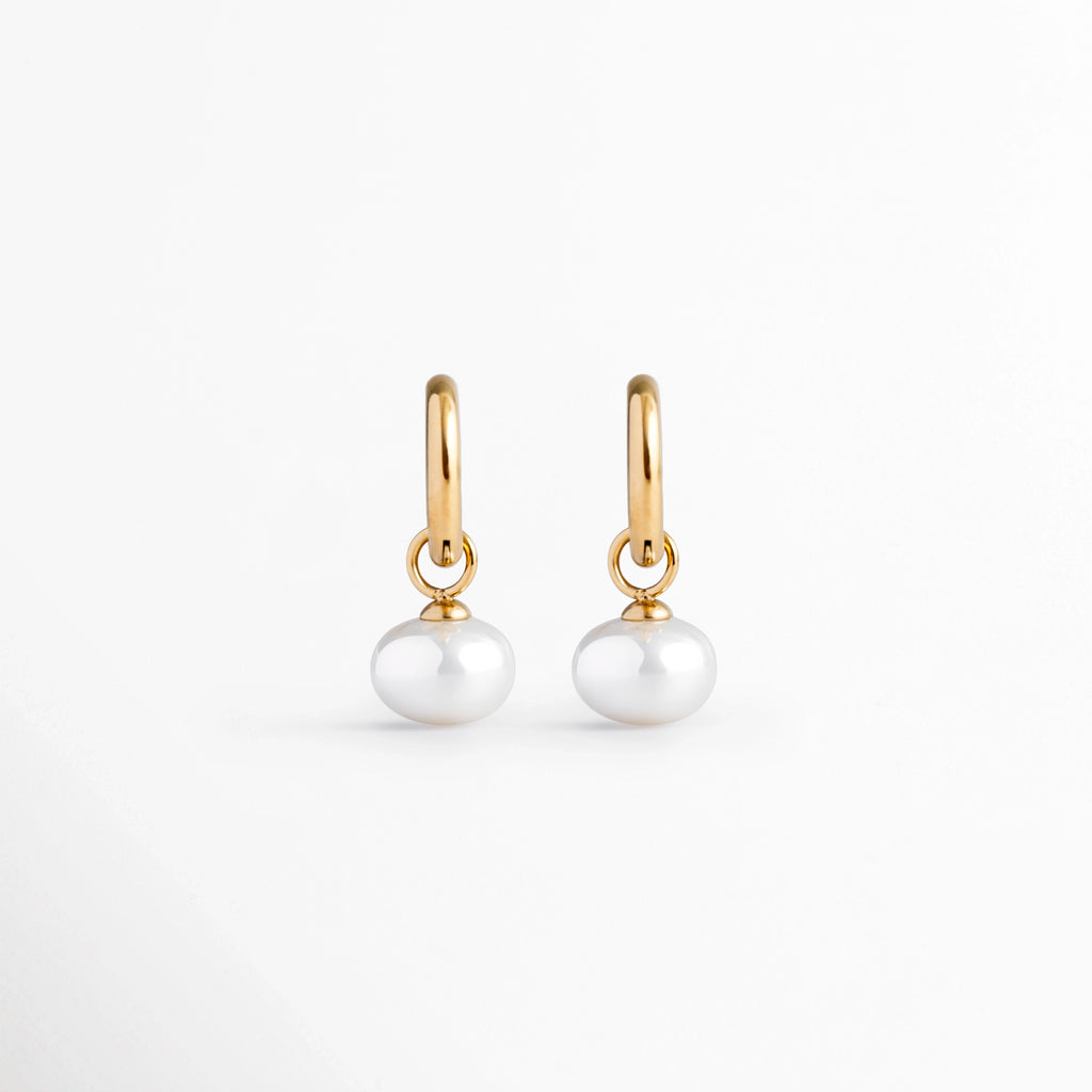 Arracadas Dune Golden Hoops enchapadas en oro 16K con perla sintética colgante en forma de lágrima, vista de frente sobre fondo blanco, Vista frontal de aretes dorados tipo huggie de 3 cm de longitud con dije colgante de perla barroca sintética, Plano general de par de arrancadas de acero inoxidable doradas con perlas sintéticas nacaradas, Dune Golden Hoops enchapadas en oro 16K destacando la elegancia orgánica de las perlas blancas colgantes de 1.3 cm de ancho.