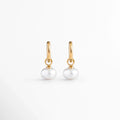 Arracadas Dune Golden Hoops enchapadas en oro 16K con perla sintética colgante en forma de lágrima, vista de frente sobre fondo blanco, Vista frontal de aretes dorados tipo huggie de 3 cm de longitud con dije colgante de perla barroca sintética, Plano general de par de arrancadas de acero inoxidable doradas con perlas sintéticas nacaradas, Dune Golden Hoops enchapadas en oro 16K destacando la elegancia orgánica de las perlas blancas colgantes de 1.3 cm de ancho.