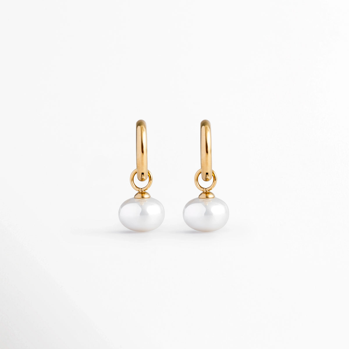 Arracadas Dune Golden Hoops enchapadas en oro 16K con perla sintética colgante en forma de lágrima, vista de frente sobre fondo blanco, Vista frontal de aretes dorados tipo huggie de 3 cm de longitud con dije colgante de perla barroca sintética, Plano general de par de arrancadas de acero inoxidable doradas con perlas sintéticas nacaradas, Dune Golden Hoops enchapadas en oro 16K destacando la elegancia orgánica de las perlas blancas colgantes de 1.3 cm de ancho.