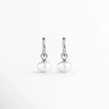 Arracadas Dune Silver Hoops enchapadas en oro blanco 16K con perla sintética colgante en forma de lágrima, vista de frente sobre fondo blanco, Vista frontal de aretes plateados tipo huggie de 3 cm de longitud con dije colgante de perla barroca sintética, Plano general de par de arracadas de acero inoxidable plateadas con perlas sintéticas nacaradas, Dune Silver Hoops enchapadas en oro blanco 16K destacando la elegancia orgánica de las perlas blancas colgantes de 1.3 cm