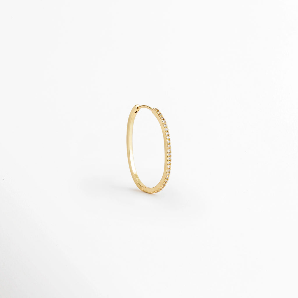 Arracada individual del Set Golden Hoops vista en perspectiva de perfil mostrando la delgada silueta dorada y el cierre continuo, Vista lateral de una arracada fina de cobre enchapada en oro 14K con perfil estilizado, Arracada de aro delgado dorada vista en ángulo de tres cuartos sobre fondo claro,  Detalle de curvatura y grosor fino de arracada con pavé de circonia incrustada.