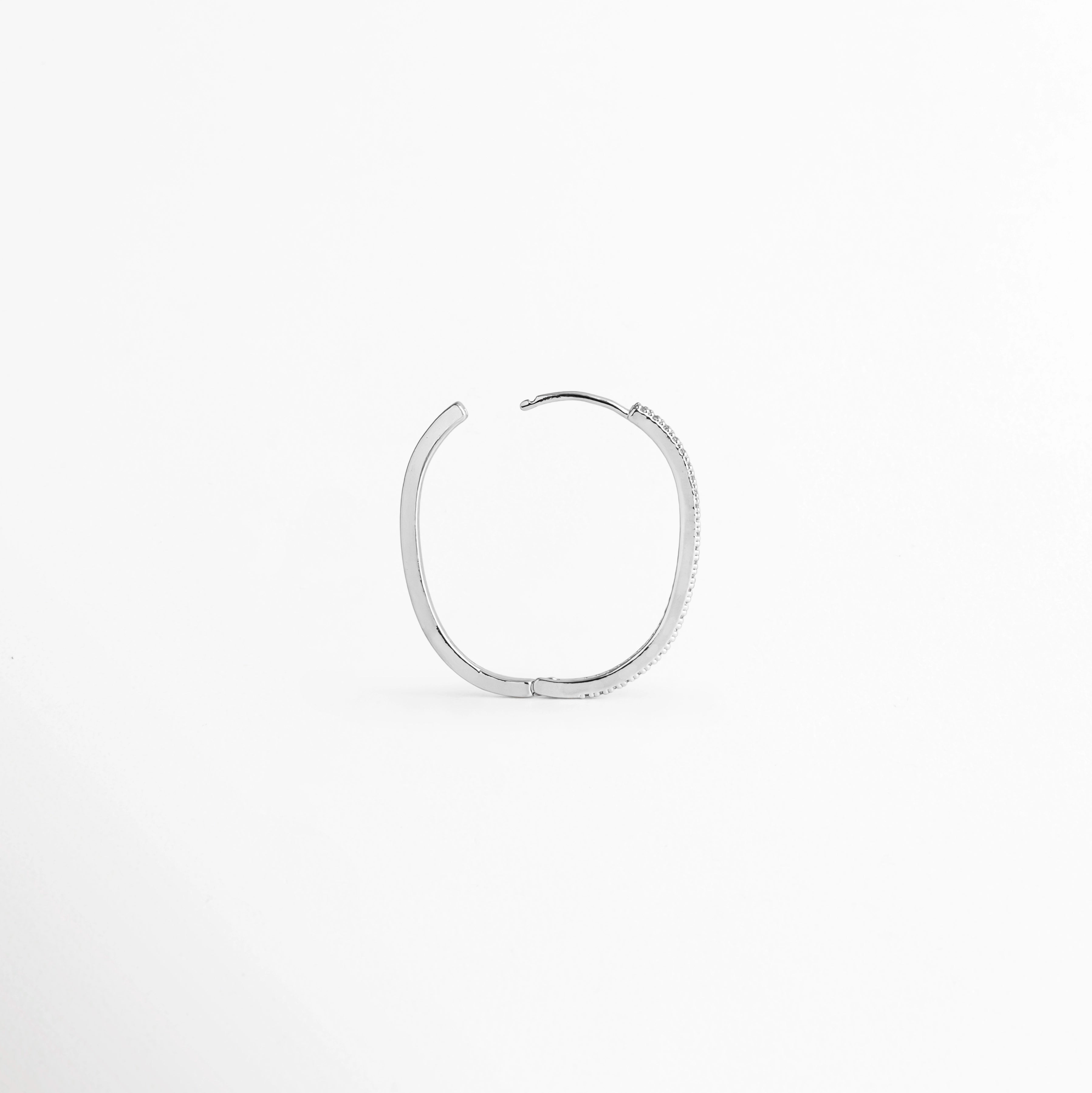 Arracada individual del Set Silver Hoops vista de perfil con la bisagra y el poste articulado abiertos para colocar en el lóbulo, Detalle del mecanismo de cierre abrible tipo hugging o clip articulado de la arracada plateada,  Vista lateral con poste flexible desplegado de aro con acabado plateado y circonias, Muestra de la abertura posterior de la arracada delgada plateada para ajuste fácil y seguro.