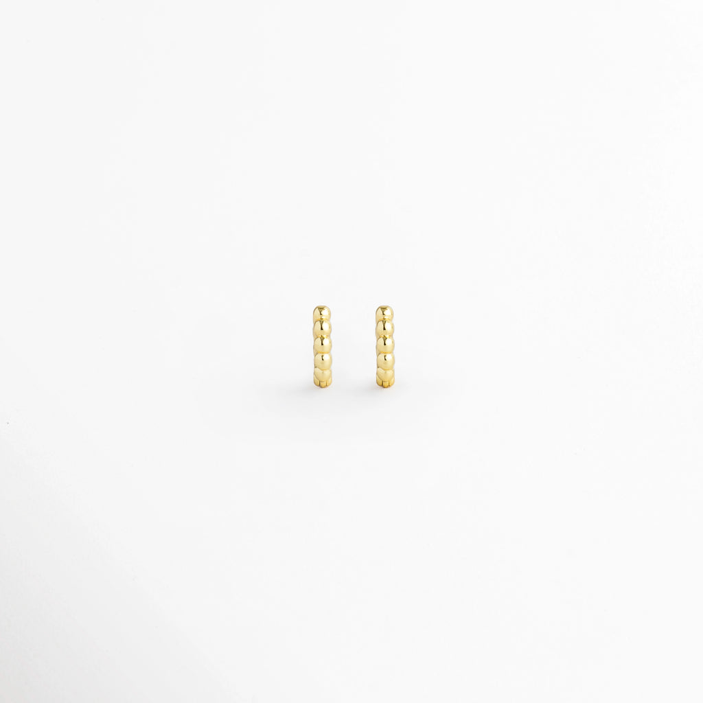 Arracada Golden de 8 mm con textura de cuentas esférias alineadas en tono dorado brillante, vista frontal de par sobre fondo blanco, Vista de frente de pequeñas arracadas doradas tipo huggie de 0.8 cm de diámetro con relieve perlado, Par de aros diminutos de 8 mm en electrochapado dorado con textura de esferas continuas y alto brillo, Arracadas doradas de 8 mm con textura de bolitas para segundo o tercer orificio sobre fondo claro.