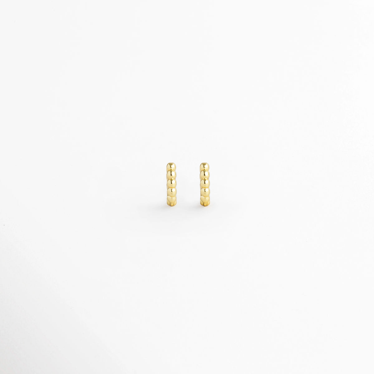 Arracada Golden de 8 mm con textura de cuentas esférias alineadas en tono dorado brillante, vista frontal de par sobre fondo blanco, Vista de frente de pequeñas arracadas doradas tipo huggie de 0.8 cm de diámetro con relieve perlado, Par de aros diminutos de 8 mm en electrochapado dorado con textura de esferas continuas y alto brillo, Arracadas doradas de 8 mm con textura de bolitas para segundo o tercer orificio sobre fondo claro.