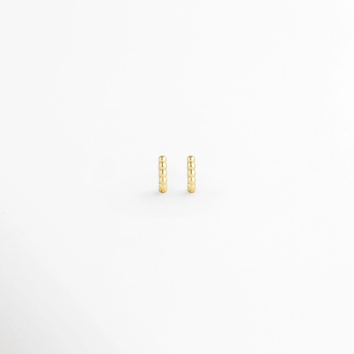 Arracada Golden de 6 mm con textura de cuentas esféricas alineadas en tono dorado brillante, vista frontal de par sobre fondo blanco, Vista de frente de micro arracadas doradas tipo huggie de 0.6 cm de diámetro con relieve perlado, Par de aros extra pequeños de 6 mm en electrochapado dorado con textura de esferas continuas y alto brillo, Arracadas doradas de 6 mm con textura de bolitas para cartílago, tragus o tercer orificio sobre fondo claro.