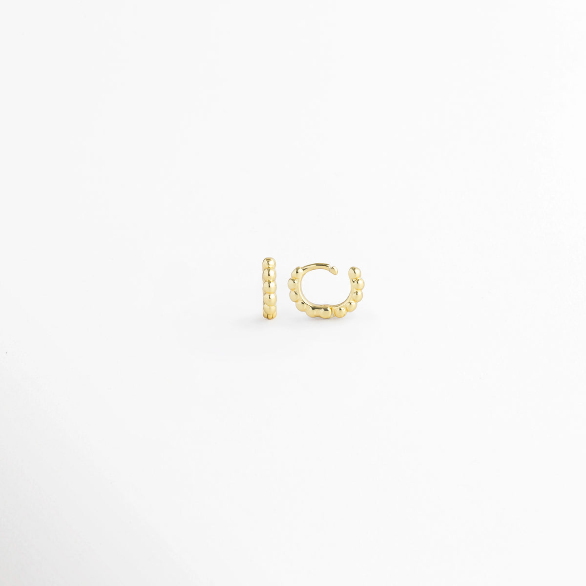 Vista lateral de la Arracada Golden de 6 mm con la bisagra completamente abierta mostrando el poste delgado, Acercamiento al broche articulado abierto de la mini arracada dorada con textura de bolitas de 0.6 cm, Detalle del sistema de apertura fácil del micro aro huggie de 6 mm sobre fondo claro, Muestra de la precisión de la bisagra en la arracada ultra pequeña de cuentas doradas de 6 mm.