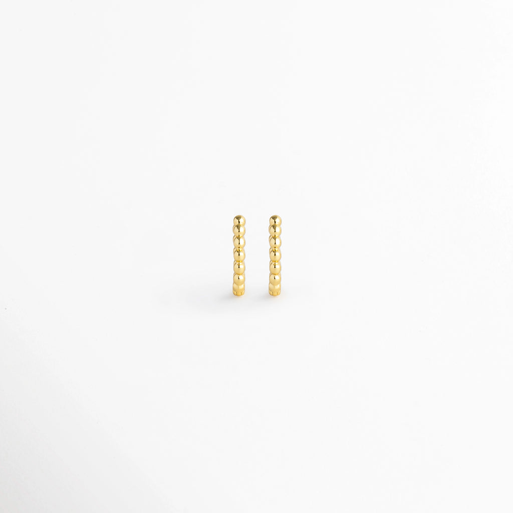Arracadas Golden Hoops de diseño perlado o de esferas continuas en tono dorado brillante, vista frontal de par sobre fondo blanco, Vista de frente de pequeñas arracadas doradas con textura de cuentas esférias alineadas en relieve, Par de aros tipo huggie dorados con textura punteada / perlada y acabado pulido espejo, Arracadas doradas textura de bolitas de estilo minimalista en electrochapado de alta durabilidad.