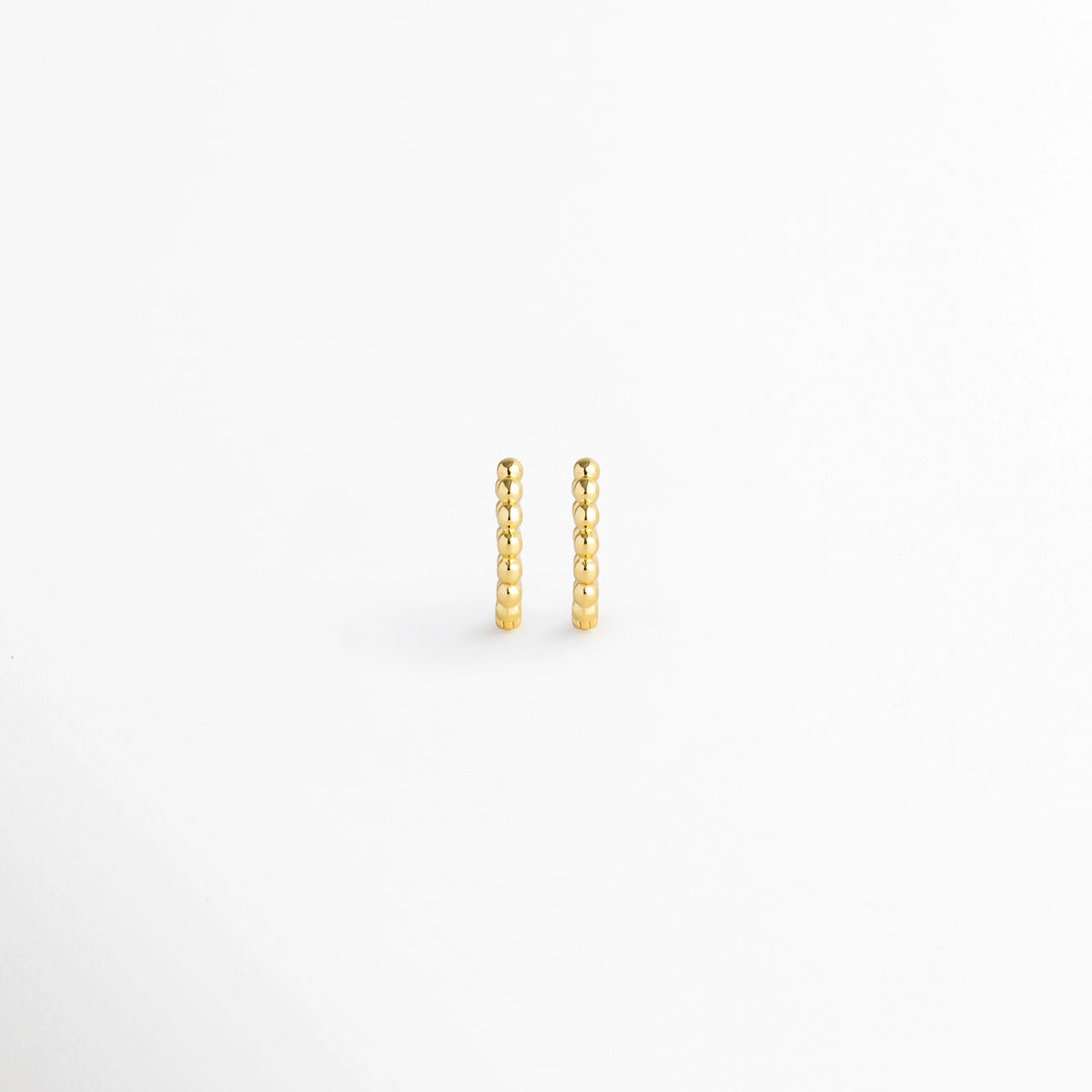 Arracadas Golden Hoops de diseño perlado o de esferas continuas en tono dorado brillante, vista frontal de par sobre fondo blanco, Vista de frente de pequeñas arracadas doradas con textura de cuentas esférias alineadas en relieve, Par de aros tipo huggie dorados con textura punteada / perlada y acabado pulido espejo, Arracadas doradas textura de bolitas de estilo minimalista en electrochapado de alta durabilidad.
