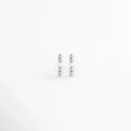 Aretes Silver Pearl Hoops de cobre con recubrimiento electrochapado plateado compuestas por una secuencia de esferas metálicas y una perla central, vista frontal sobre fondo blanco, Vista de frente de par de arracadas pequeñas plateadas con textura esférica rítmica y perla blanca en el centro, Plano general de arracadas Huggie en tono plata con perla sintética engastada y cuentas metálicas pulidas sobre fondo neutro,  Silver Pearl Hoops destacando la combinación