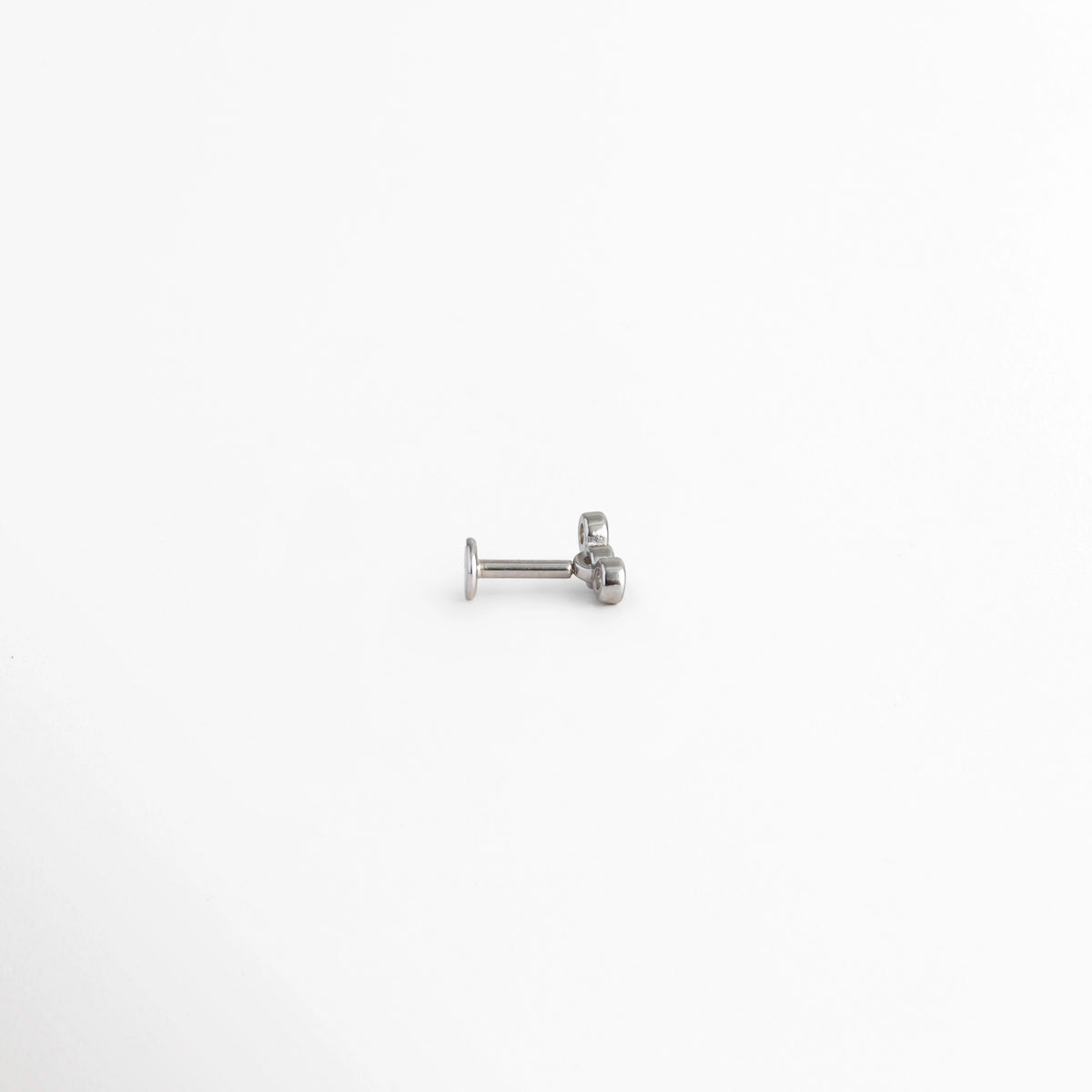 Piercing Lorena visto de perfil mostrando el poste recto con base discoid plana tipo labret y el frente de moissanitas, Detalle lateral de piercing de Plata 925 con disco posterior plano ideal para confort en la oreja, Vista de costado del poste de plata enchapada con base plana para cartílago, tragus o conch, Perspectiva de perfil de piercing labret plateado con incrustaciones de moissanita y acabado brillante.