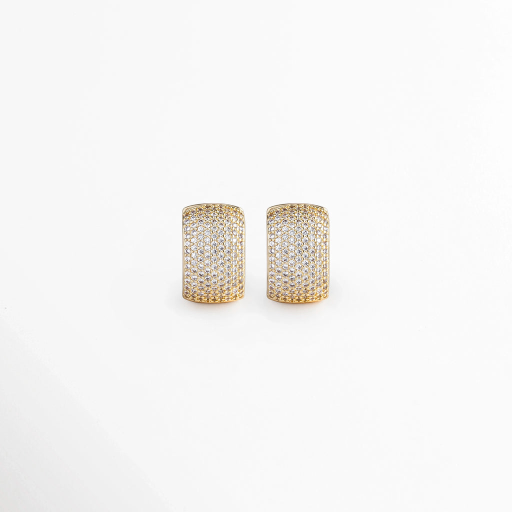 Aretes Bori Golden de diseño huggie ancho enchapados en oro 18K con cuajado denso de micro-pedrería brillante en pavé, vista frontal sobre fondo blanco, Vista de frente de aretes tipo arrancada ancha abombada de 1.8 cm de largo con incrustación continua de piedras preciosas artificiales, Plano general de aretes dorados gruesos estilo huggie cuajados de micro-circonias transparentes sobre fondo neutro, Aretes Bori Golden destacando el brillo deslumbrante del pavé