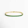 Tennis Bracelet Green Grace enchapada en oro 18K con hilera continua de circonias verde esmeralda de corte brillante, vista de frente sobre fondo blanco, Vista frontal de pulsera tennis delgada de 0.3 cm de ancho con gemas de circonia verde y engaste de garras doradas, Plano general de brazalete estilo tennis de cobre enchapado en oro 18K con pedrería verde brillante, Tennis Bracelet Green Grace mostrando la secuencia uniforme de circonias verdes de 18 cm