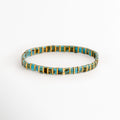 Pulsera Rectángulos Aquamarina elaborada con cuentas Tila en tonos turquesa y dorado sobre fondo blanco, Vista frontal de la Pulsera Rectángulos Aquamarina con diseño elástico de cuentas rectangulares, Pulsera Rectángulos Aquamarina con cuentas Tila turquesa y doradas de estilo minimalista, Pulsera elástica Rectángulos Aquamarina con cuentas rectangulares en colores turquesa y dorado, Pulsera Rectángulos Aquamarina con diseño moderno de cuentas Tila sobre fondo blanco.