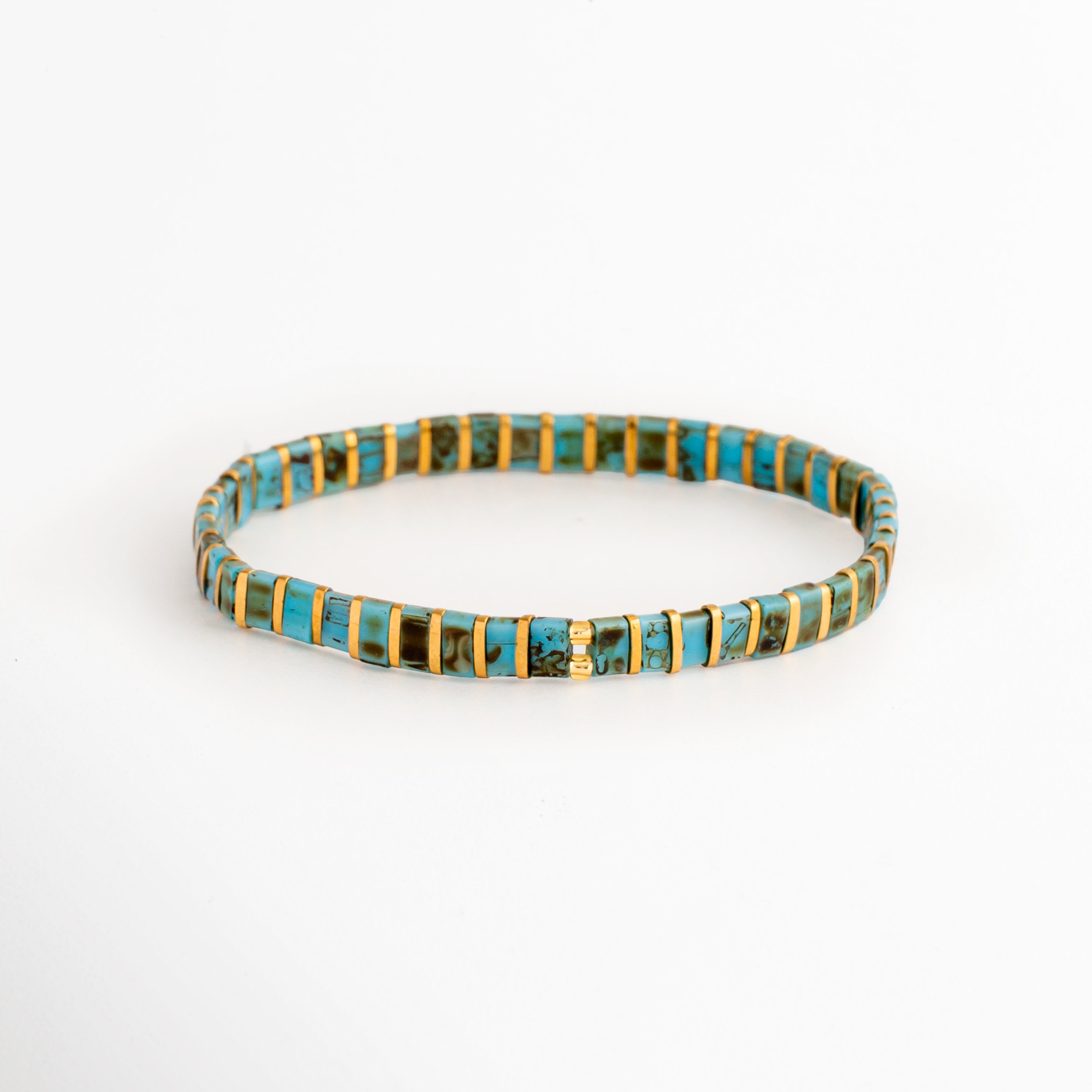 Pulsera Rectángulos Aquamarina elaborada con cuentas Tila en tonos turquesa y dorado sobre fondo blanco, Vista frontal de la Pulsera Rectángulos Aquamarina con diseño elástico de cuentas rectangulares, Pulsera Rectángulos Aquamarina con cuentas Tila turquesa y doradas de estilo minimalista, Pulsera elástica Rectángulos Aquamarina con cuentas rectangulares en colores turquesa y dorado, Pulsera Rectángulos Aquamarina con diseño moderno de cuentas Tila sobre fondo blanco.