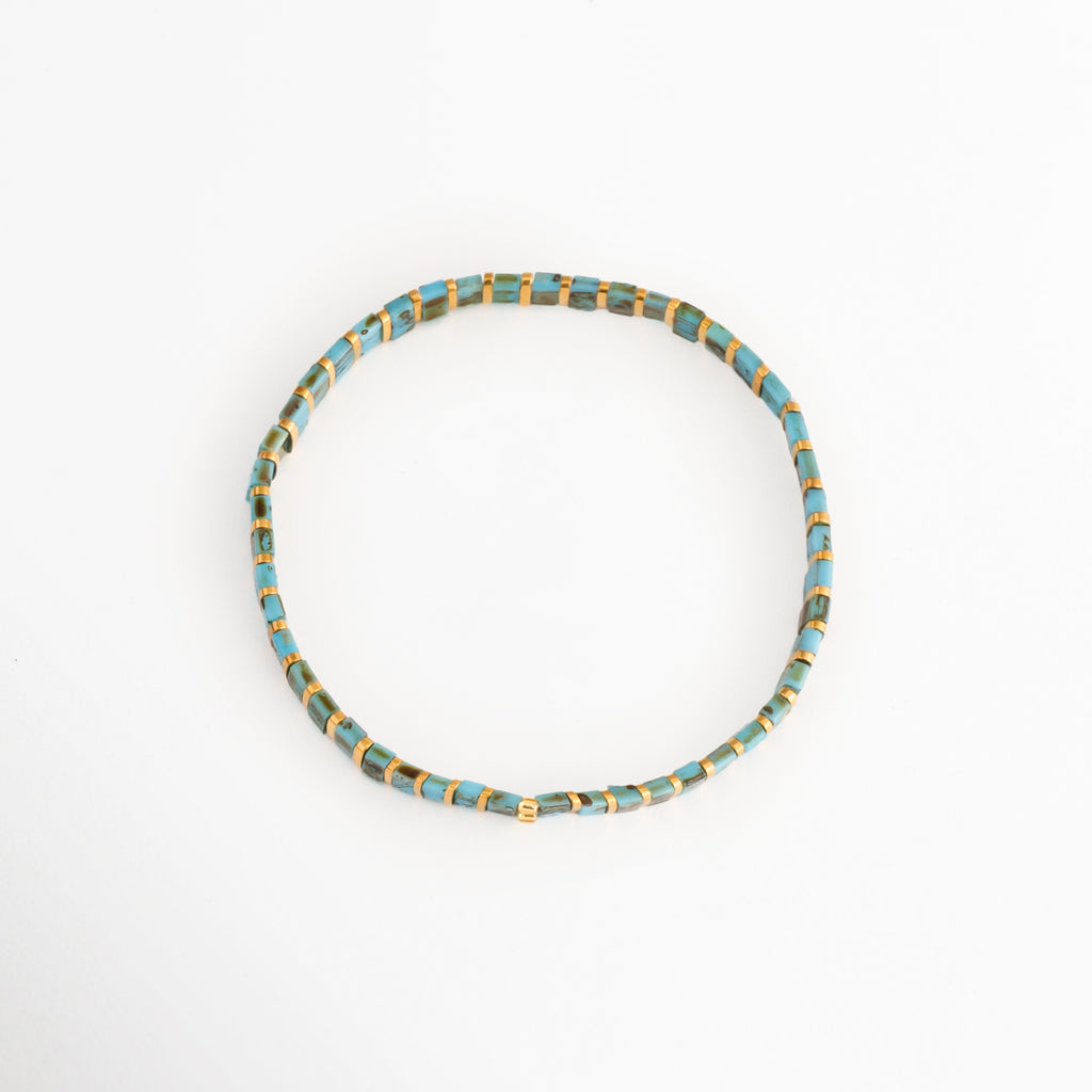 Vista en ángulo de la Pulsera Rectángulos Aquamarina mostrando su diseño circular con cuentas Tila, Perspectiva de la Pulsera Rectángulos Aquamarina con cuentas rectangulares en tonos turquesa y dorado, Pulsera Rectángulos Aquamarina fotografiada en perspectiva resaltando su diseño elástico, Vista diagonal de la Pulsera Rectángulos Aquamarina con cuentas Tila de colores, Pulsera Rectángulos Aquamarina en perspectiva con diseño minimalista y acabado colorido.