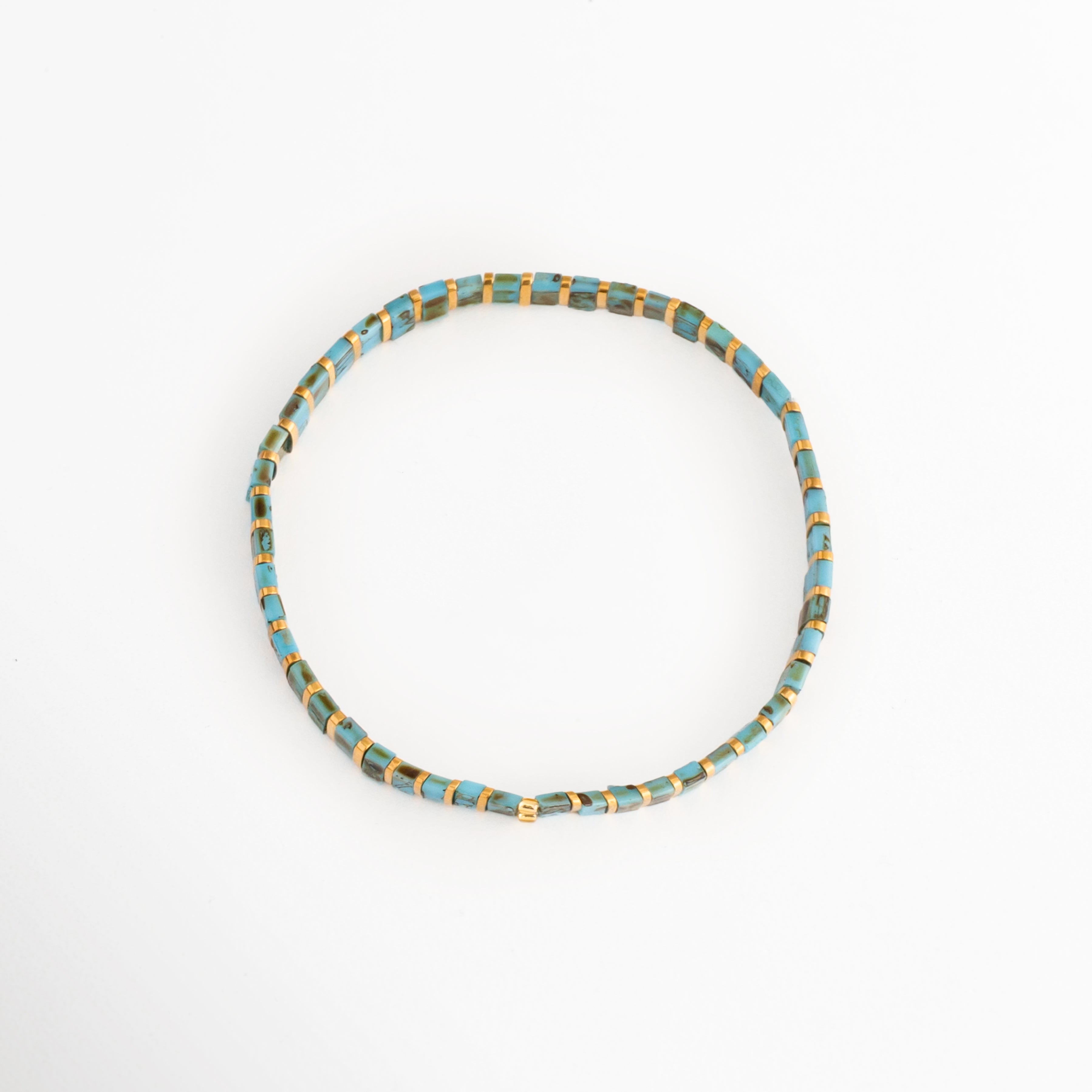 Vista en ángulo de la Pulsera Rectángulos Aquamarina mostrando su diseño circular con cuentas Tila, Perspectiva de la Pulsera Rectángulos Aquamarina con cuentas rectangulares en tonos turquesa y dorado, Pulsera Rectángulos Aquamarina fotografiada en perspectiva resaltando su diseño elástico, Vista diagonal de la Pulsera Rectángulos Aquamarina con cuentas Tila de colores, Pulsera Rectángulos Aquamarina en perspectiva con diseño minimalista y acabado colorido.
