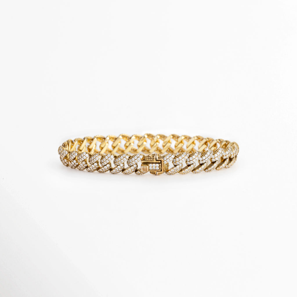 Vista en perspectiva de la Pulsera Golden Margot mostrando el broche de caja seguro integrado con pedrería en los eslabones cubanos, Acercamiento a la cara posterior del cierre plegable de la pulsera dorada enchapada en oro 18K, Toma en ángulo que resalta la solidez y el pulido espejo de la plata ley 925 en el broche de la cadena, Muestra del mecanismo de sujeción tipo reloj para un ajuste firme en la pulsera de 16 cm de longitud. 