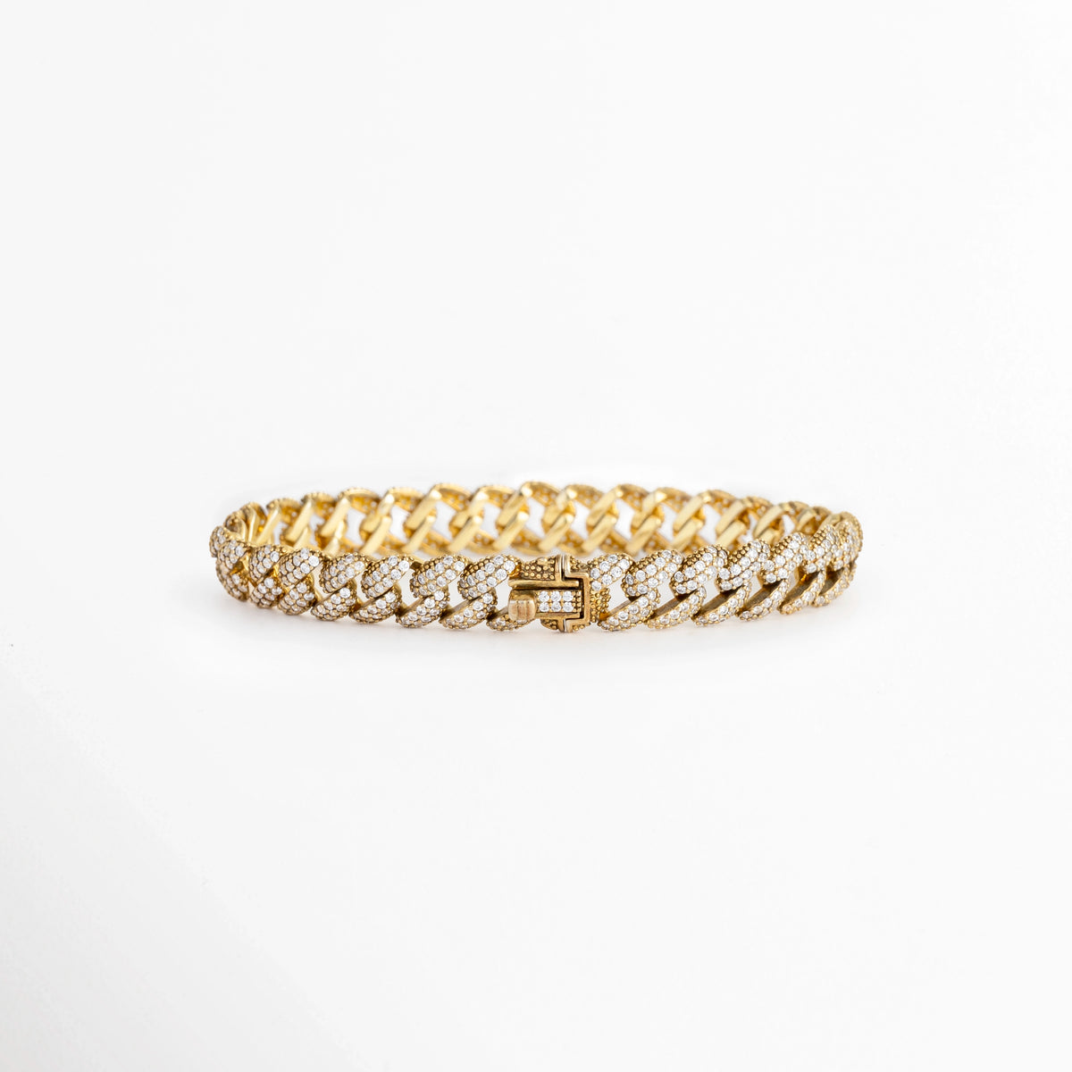 Vista en perspectiva de la Pulsera Golden Margot mostrando el broche de caja seguro integrado con pedrería en los eslabones cubanos, Acercamiento a la cara posterior del cierre plegable de la pulsera dorada enchapada en oro 18K, Toma en ángulo que resalta la solidez y el pulido espejo de la plata ley 925 en el broche de la cadena, Muestra del mecanismo de sujeción tipo reloj para un ajuste firme en la pulsera de 16 cm de longitud. 