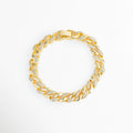 Pulsera Brock de eslabones estilo barbada cubana enchapada en oro 18K con incrustaciones de circonias tipo CZ en media cara, vista superior sobre fondo blanco, Vista de frente de gargantilla o pulsera cubana dorada de 0.6 cm de ancho con pavé de circonias transparentes sobre eslabones entrelazados, Plano general de cadena tipo cubana de cobre enchapada en oro 18K con destellos de pedrería fina sobre fondo neutro, Pulsera Brock destacando la simetría de sus eslabones