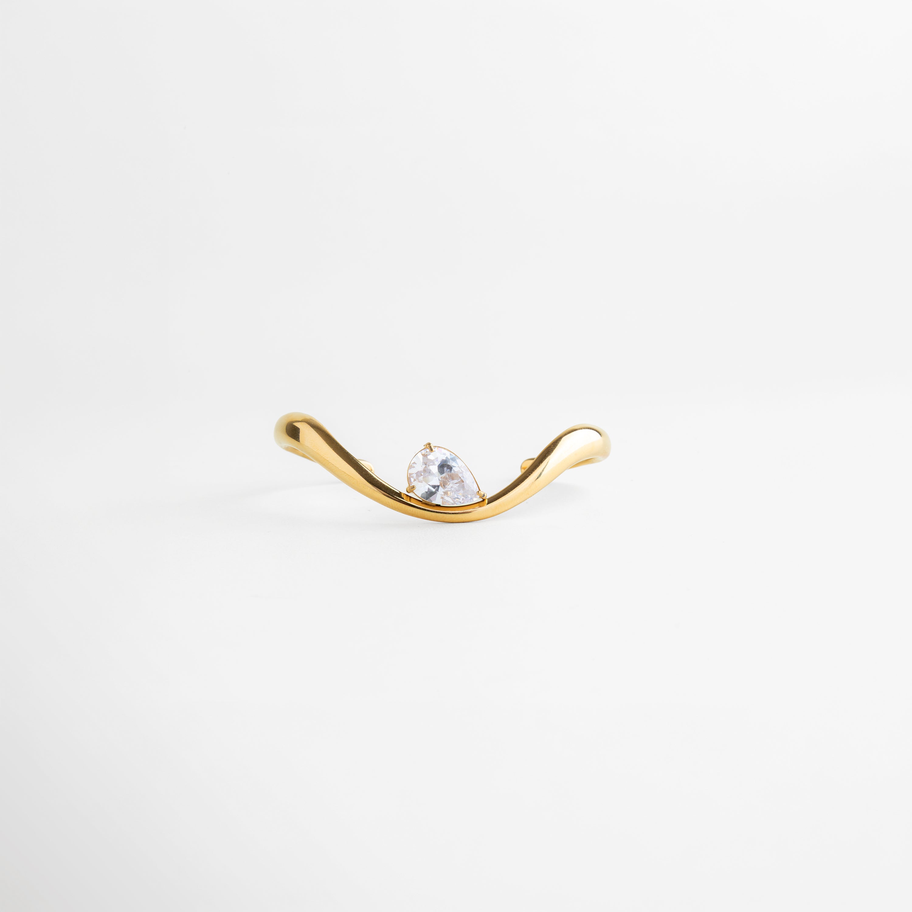 Vista frontal de pulsera dorada con zirconia en el centro, Pulsera tipo cuff con diseño simétrico y acabado pulido, Pulsera abierta con piedra zirconia brillante y estilo minimalista, Pulsera elegante con forma curva y detalle central, Pulsera ajustable dorada con diseño moderno y sofisticado