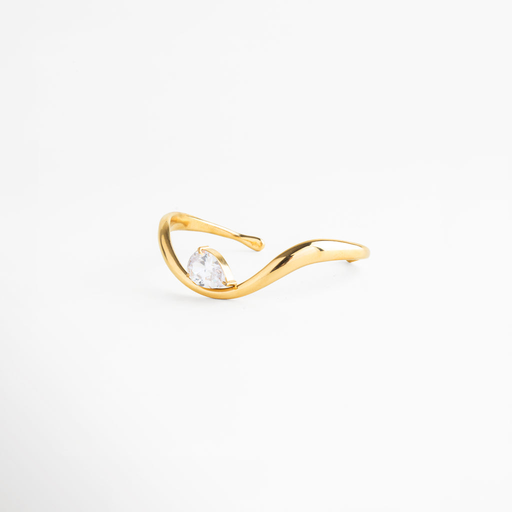 Vista lateral de pulsera abierta con zirconia y acabado en oro 18K, Pulsera ajustable con diseño curvo y detalle brillante en zirconia, Perfil de pulsera tipo cuff con forma fluida y acabado dorado, Pulsera moderna con estructura abierta y piedra central, Detalle lateral de pulsera elegante con zirconia incrustada