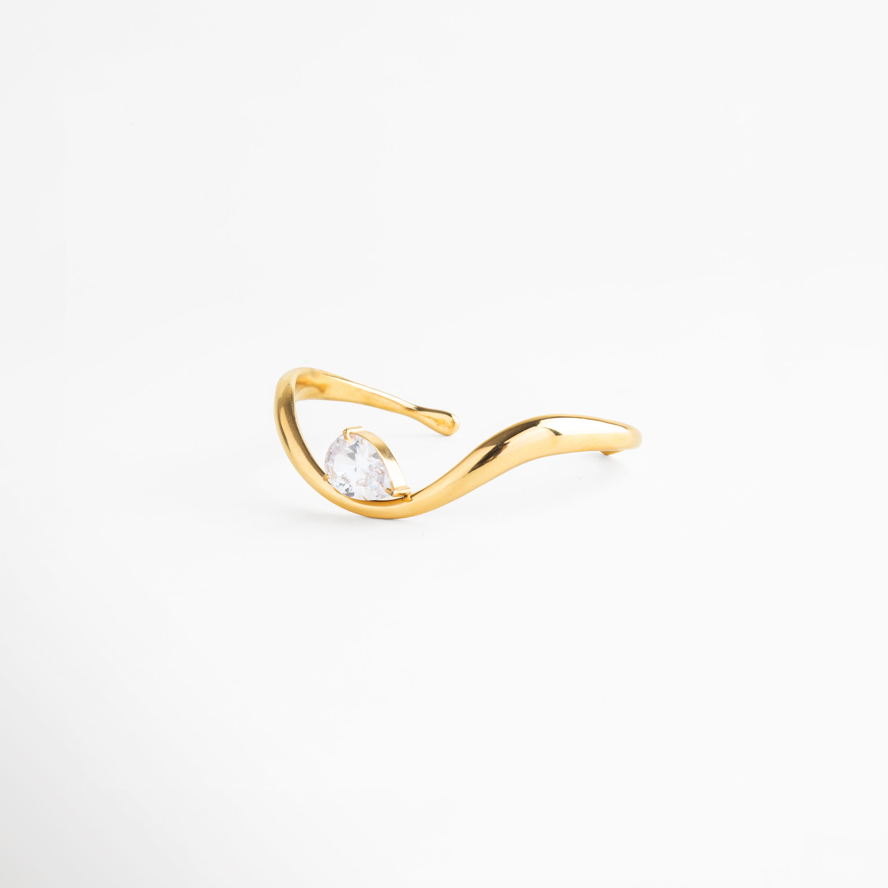Vista lateral de pulsera abierta con zirconia y acabado en oro 18K, Pulsera ajustable con diseño curvo y detalle brillante en zirconia, Perfil de pulsera tipo cuff con forma fluida y acabado dorado, Pulsera moderna con estructura abierta y piedra central, Detalle lateral de pulsera elegante con zirconia incrustada