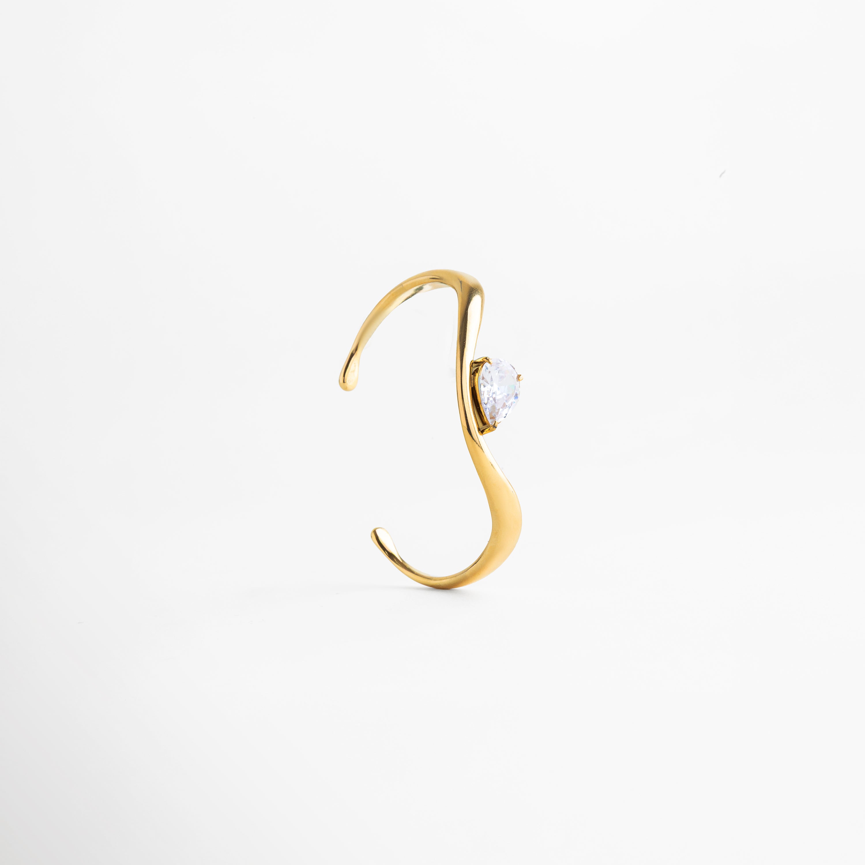 Pulsera tipo cuff ajustable en acero inoxidable 304 con baño de oro 18K y zirconia, Pulsera abierta dorada con zirconia central, diseño elegante y moderno, Pulsera rígida con acabado en oro 18K y piedra zirconia brillante, Pulsera minimalista ajustable con diseño fluido y zirconia incrustada, Pulsera contemporánea dorada con forma orgánica y detalle de zirconia