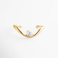 Pulsera dorada en ángulo con zirconia y diseño escultórico, Vista diagonal de pulsera ajustable con acabado brillante, Pulsera moderna con forma orgánica y piedra zirconia, Pulsera de lujo con diseño fluido y acabado en oro 18K, Pulsera minimalista con detalle brillante y estilo contemporáneo