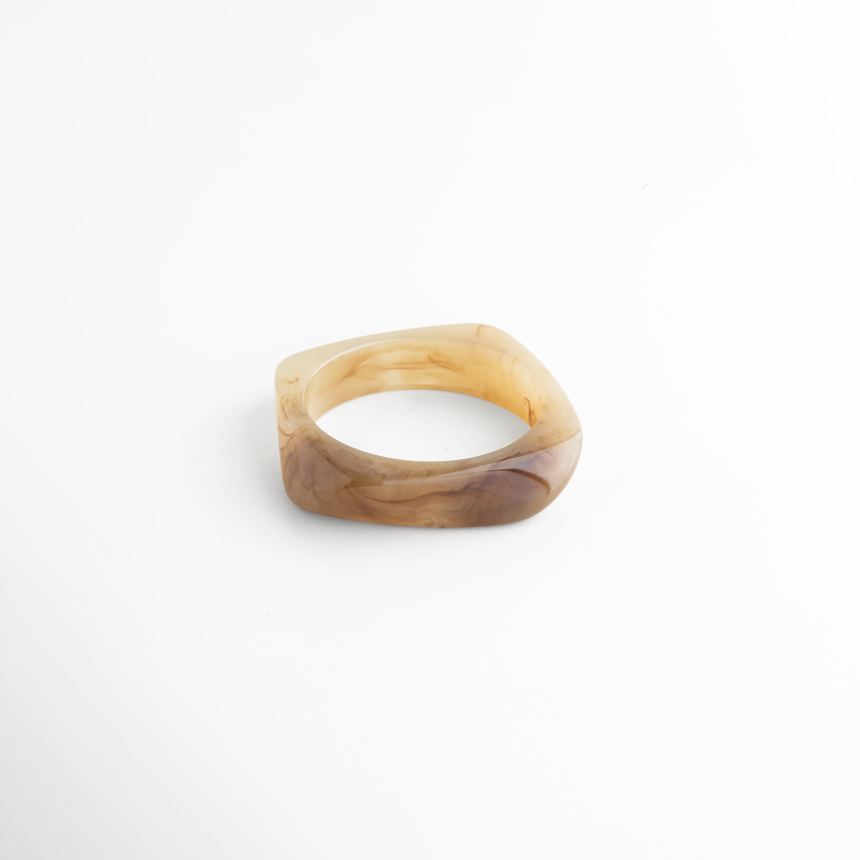 Vista lateral de pulsera de resina con grosor uniforme, Pulsera de resina con diseño estructurado y acabado brillante, Perfil de pulsera rígida con textura suave y pulida, Pulsera moderna con acabado translúcido y forma orgánica, Detalle lateral de pulsera minimalista de resina