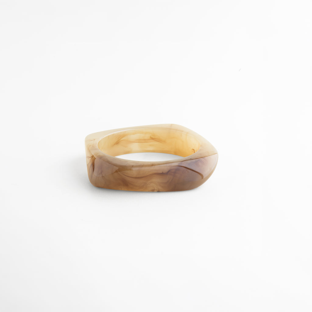 Pulsera de resina en ángulo con acabado marmoleado elegante, Vista diagonal de pulsera chunky con efecto translúcido, Pulsera moderna de resina con diseño limpio y sofisticado, Pulsera de resina con acabado brillante en tonos cálidos, Pulsera minimalista con diseño orgánico contemporáneo