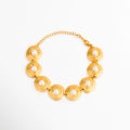 Pulsera Khalira de eslabones circulares dorados con incrustaciones de perlas blancas, Pulsera de acero inoxidable chapada en oro de 18K con detalles de perlas de alto brillo, Joyería elegante: pulsera dorada con dijes redondos y perlas centrales sobre fondo blanco, Pulsera ajustable de eslabones planos de oro con perlas clásicas de imitación, Vista completa de la pulsera Khalira mostrando su cadena extensoria y broche.