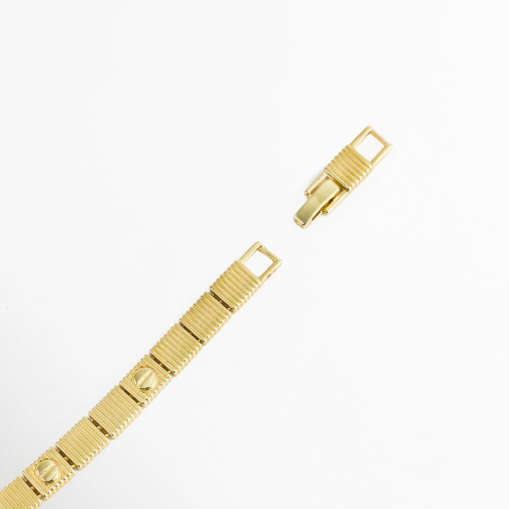 Acercamiento al broche plegable desplegado y eslabón de extensión desmontable de la Pulsera Golden Alba, Vista macro del sistema de cierre de broche tipo reloj en acero inoxidable enchapado en oro 18K, Detalle de las placas cuadradas con motivo de tornillo y el mecanismo de sujeción ajustable sobre fondo blanco, Muestra de la extensión desmontable de 3 cm que permite ajustar la pulsera de 17 cm a 20 cm.