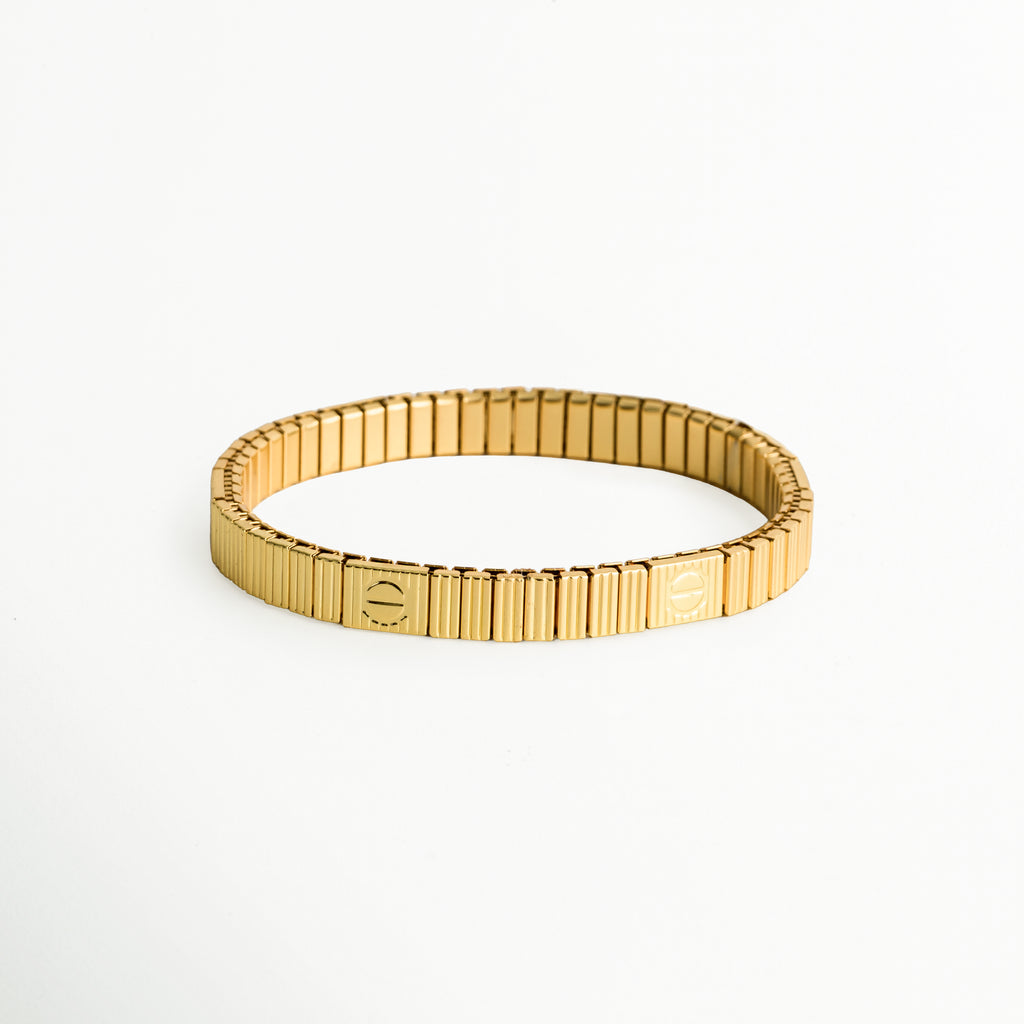 Pulsera Golden Vega elástica en tono dorado con eslabones rectangulares acanalados tipo oruga e insignias grabadas, vista frontal sobre fondo blanco, Brazalete extensible de acero inoxidable enchapado en oro 18K con textura acanalada de estilo reloj de lujo, Vista de frente de pulsera elástica dorada flexible de eslabones verticales pulidos con detalles de placas cuadradas grabadas, Pulsera elástica tipo stretch en oro cálido con estructura acanalada flexible.