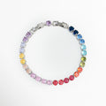 Pulsera Tennis Bracelet Rainbow enchapada en rodio con hileras de circonias circulares en degradé multicolor de arcoíris, vista frontal en círculo sobre fondo blanco, Brazalete estilo tennis de 17 cm más extensión de 2.5 cm con gemas de circonia en tonos azul, verde, amarillo, rosa y rojo, Vista de frente de pulsera de cobre enchapada en rodio con bisel de gemas cristalinas de colores en degradé, Pulsera estilo riviera o tennis multicolor de 0.5 cm de ancho.