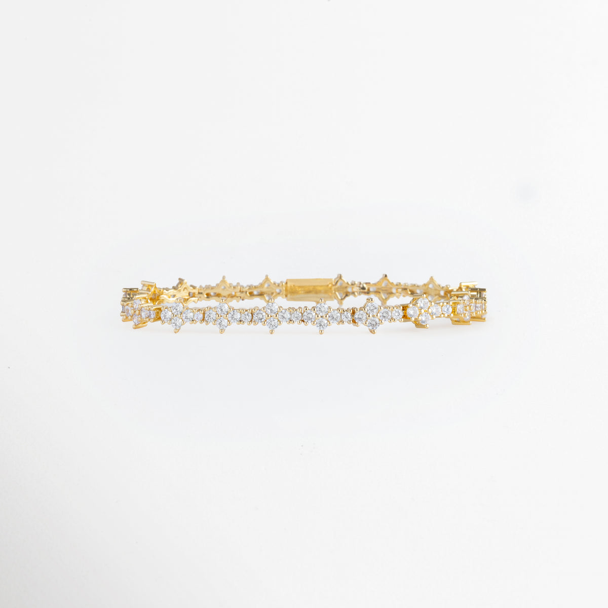 Pulsera Golden Musa enchapada en oro con motivos florales de cuatro pétalos de circonia transparente, vista frontal sobre fondo blanco, Vista de frente de brazalete dorado de 0.7 cm de ancho con secuencia continua de rosetas y flores de pedrería brillante, Plano general de pulsera articulada de cobre enchapada en oro con eslabones florales de circonias cristalinas, Pulsera Golden Musa mostrando la simetría de sus motivos estelares y florales en tono oro de 18 cm 