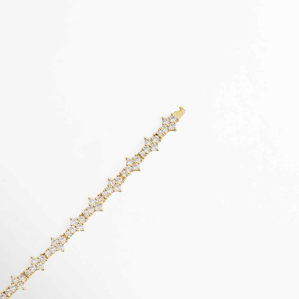  Acercamiento a la línea de eslabones florales de la Pulsera Golden Musa mostrando el detalle de engaste de cada circonia, Vista en ángulo de la pulsera extendida resaltando el brillo del acabado enchapado en oro sobre la estructura de cobre, Toma en perspectiva que muestra el diseño geométrico y floral de los motivos de pedrería transparente, Muestra de la alineación y relieve de los pétalos de circonia de 0.7 cm de ancho.