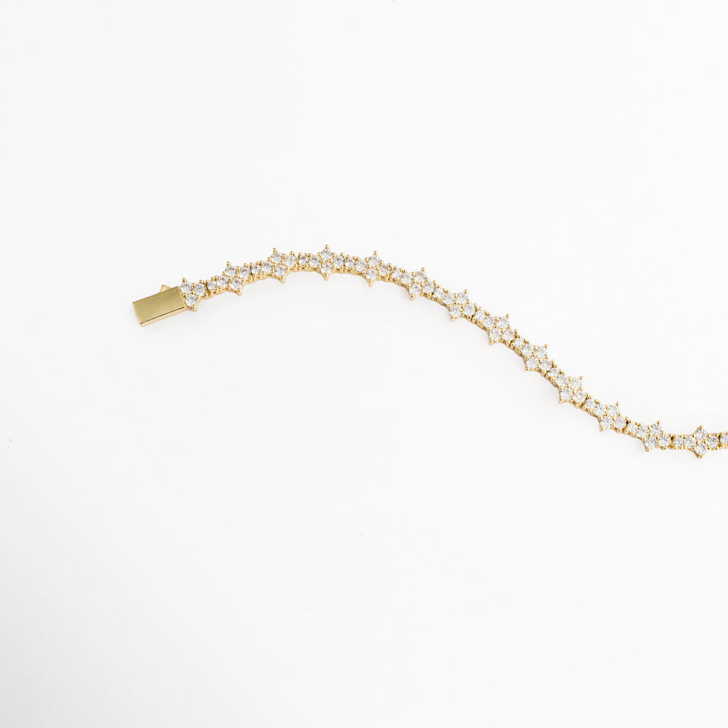 Vista en curva suave de la Pulsera Golden Musa destacando la flexibilidad de sus articulaciones y el destello de la pedrería, Acercamiento a la fluidez del brazalete de motivos florales con acabado dorado brillante, Toma de perfil articulado que resalta el resplandor de las circonias transparentes con el movimiento, Muestra de los destellos cálidos del enchapado en oro combinado con el corte brillante de las circonias. 
