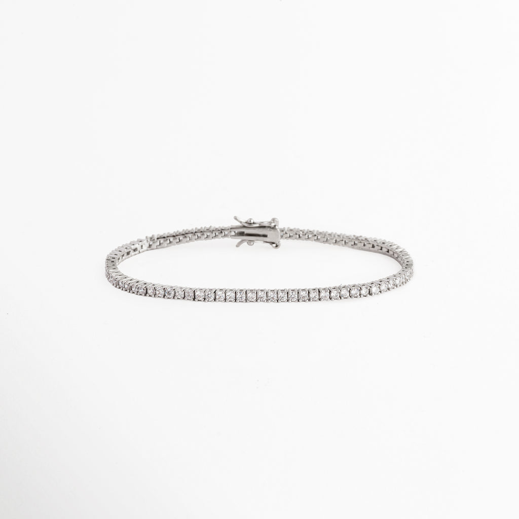 Tennis Bracelet Beloved enchapada en oro blanco con hilera continua de circonias transparentes de corte brillante, vista de frente sobre fondo blanco, Vista frontal de pulsera tennis ultradelgada de 0.2 cm de ancho con engaste de garras plateadas y pedrería brillante, Plano general de brazalete estilo tennis de cobre enchapado en oro blanco de 18 cm de longitud sobre fondo neutro, Tennis Bracelet Beloved destacando la secuencia uniforme