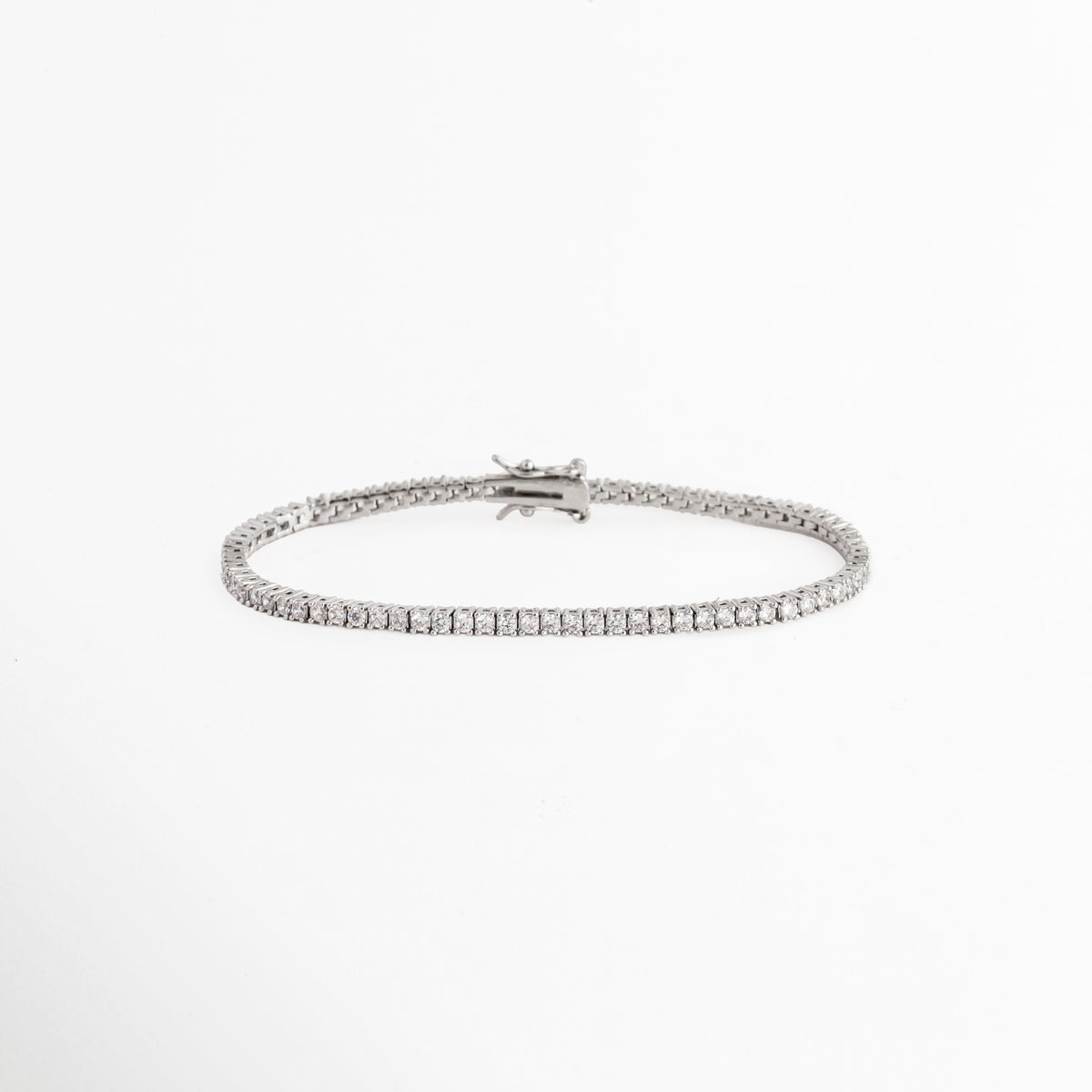 Tennis Bracelet Beloved enchapada en oro blanco con hilera continua de circonias transparentes de corte brillante, vista de frente sobre fondo blanco, Vista frontal de pulsera tennis ultradelgada de 0.2 cm de ancho con engaste de garras plateadas y pedrería brillante, Plano general de brazalete estilo tennis de cobre enchapado en oro blanco de 18 cm de longitud sobre fondo neutro, Tennis Bracelet Beloved destacando la secuencia uniforme