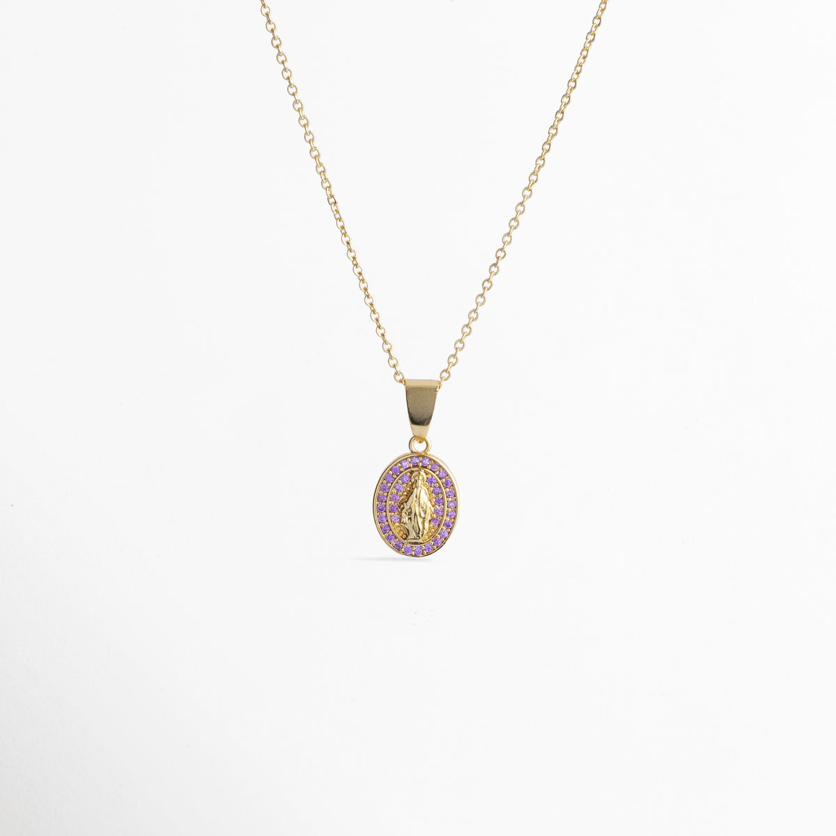 Collar Medallón Dorado Virgen de cobre enchapado en oro con dije ovalado de la Virgen y halo de circonias violeta o lila, vista frontal sobre fondo blanco, Vista de frente de collar dorado con medallón de la Virgen de Guadalupe de 2.5 cm de largo rodeado de circonias violetas brillante, Plano general de collar fino en tono oro con dije religioso ovalado y halo de pedrería lila sobre fondo neutro, Collar Medallón Dorado Virgen destacando el contraste entre la figura 