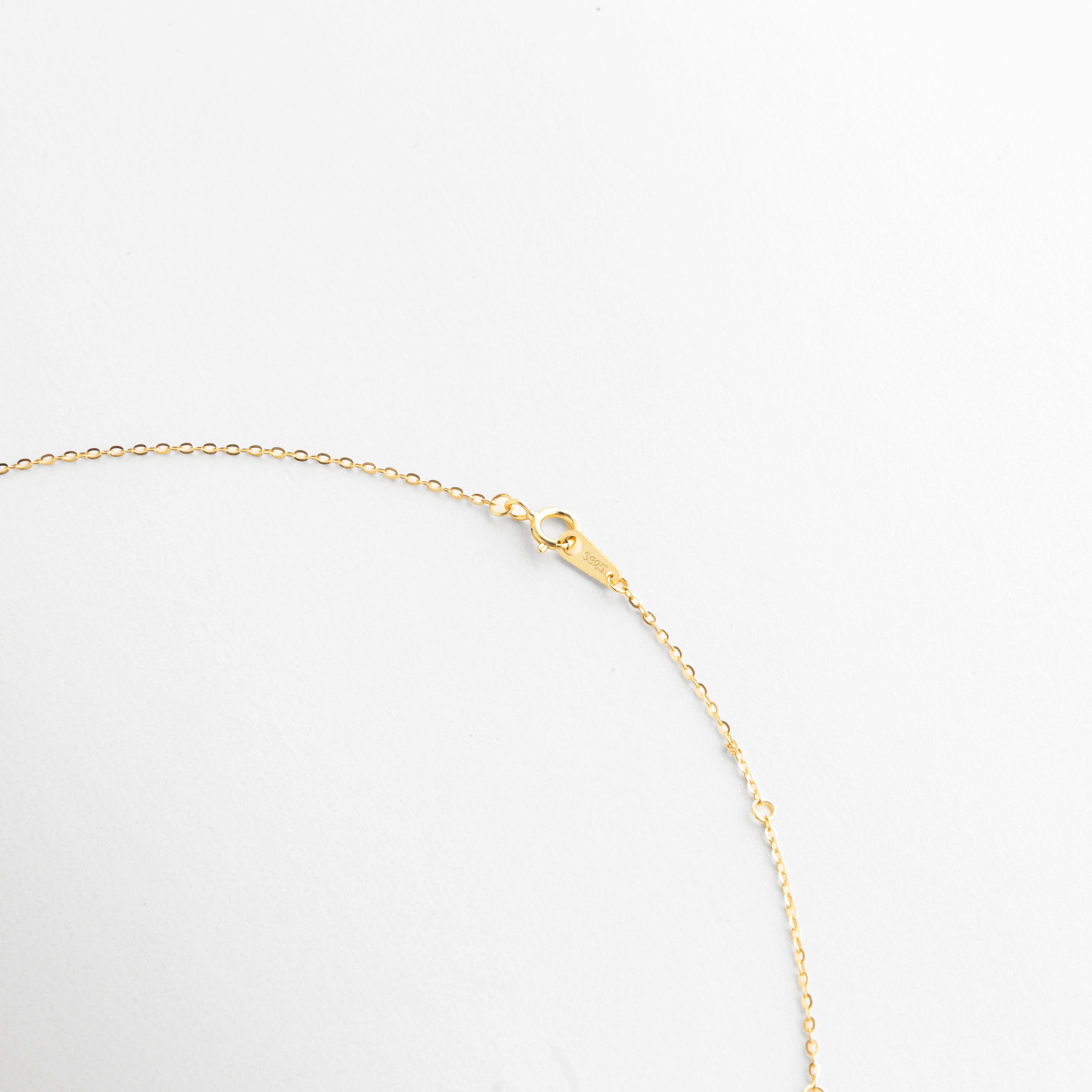 Detalle del cierre de Collar Cruz Sagrada Dorada con broche metálico y cadena fina dorada, Vista cercana del broche de collar dorado con acabado elegante y cadena delicada, Detalle del cierre tipo broche del collar de cruz dorada en Oro 18K, Close up de cadena fina dorada con broche metálico del Collar Cruz Sagrada Dorada, Detalle de collar femenino con cierre seguro y acabado dorado brillante.