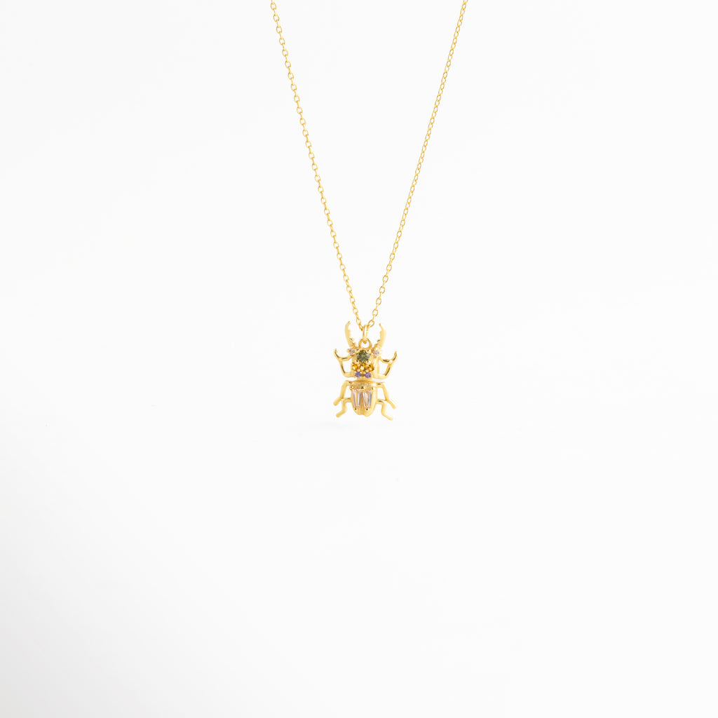 Collar Beetle dorado con dije de escarabajo y zirconias brillantes en diseño elegante, Collar delicado con dije de escarabajo en acabado oro 18K y detalles de zirconia, Cadena fina con colgante de escarabajo inspirado en un diseño místico y sofisticado, Collar de Plata Ley 925 con dije de beetle dorado y brillo sutil, Collar femenino con colgante de escarabajo y acabado refinado en oro y plata.