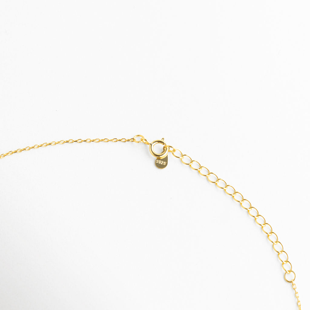 Detalle del cierre de Collar Ópalo con broche metálico y cadena fina dorada, Vista cercana del broche del collar dorado con acabado delicado y elegante, Detalle del cierre tipo broche del Collar Ópalo en cadena fina, Close up de collar con cierre seguro y acabado dorado brillante, Detalle de cadena fina con broche metálico del Collar Ópalo.