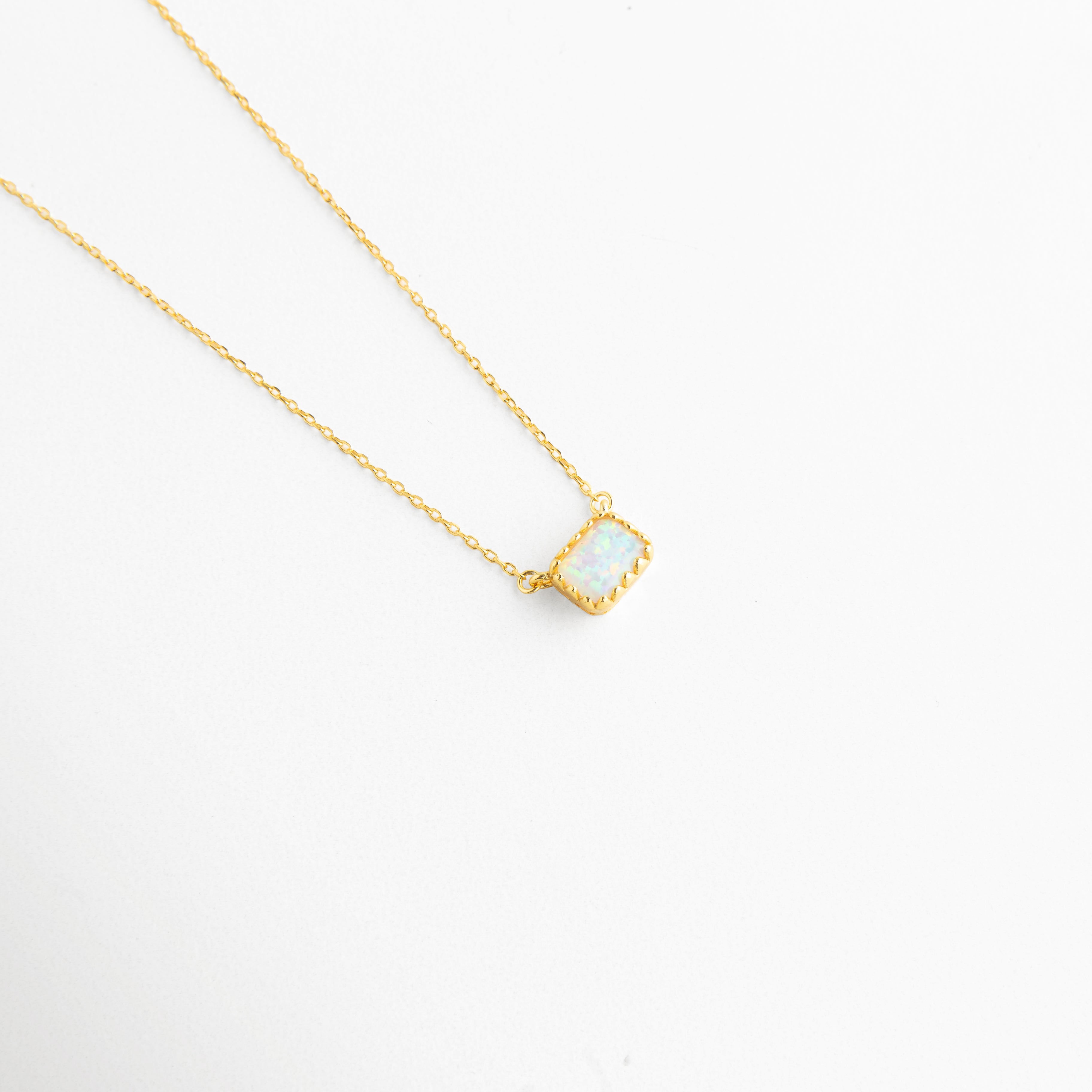 Vista inclinada de Collar Ópalo con dije pequeño y acabado dorado elegante, Detalle del colgante con piedra de ópalo en cadena fina dorada, Collar Ópalo en vista diagonal con diseño femenino y minimalista, Cadena dorada delicada con dije de ópalo y brillo sutil, Detalle de collar refinado con piedra de ópalo y estilo atemporal.
