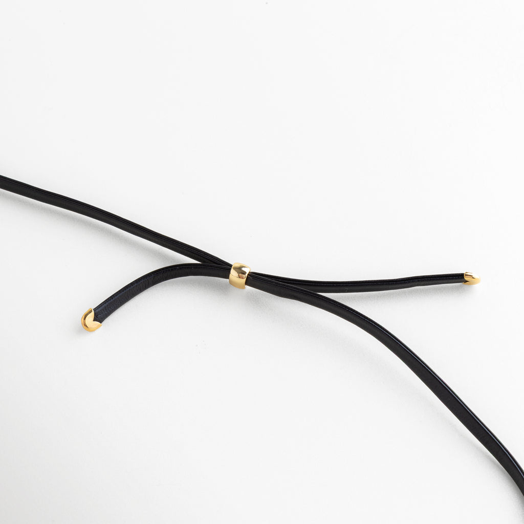 Primer plano del pasador dorado ajustable en el cordón de cuero del collar, Detalle de los terminales enchapados en oro en las puntas del cordón negro, Mecanismo de ajuste del collar Gold Monet con componentes de oro 18K, Zoom a los acabados de calidad en el cordón de cuero y herrajes dorados, Vista técnica del cierre y puntas del collar que muestra el baño de oro premium.